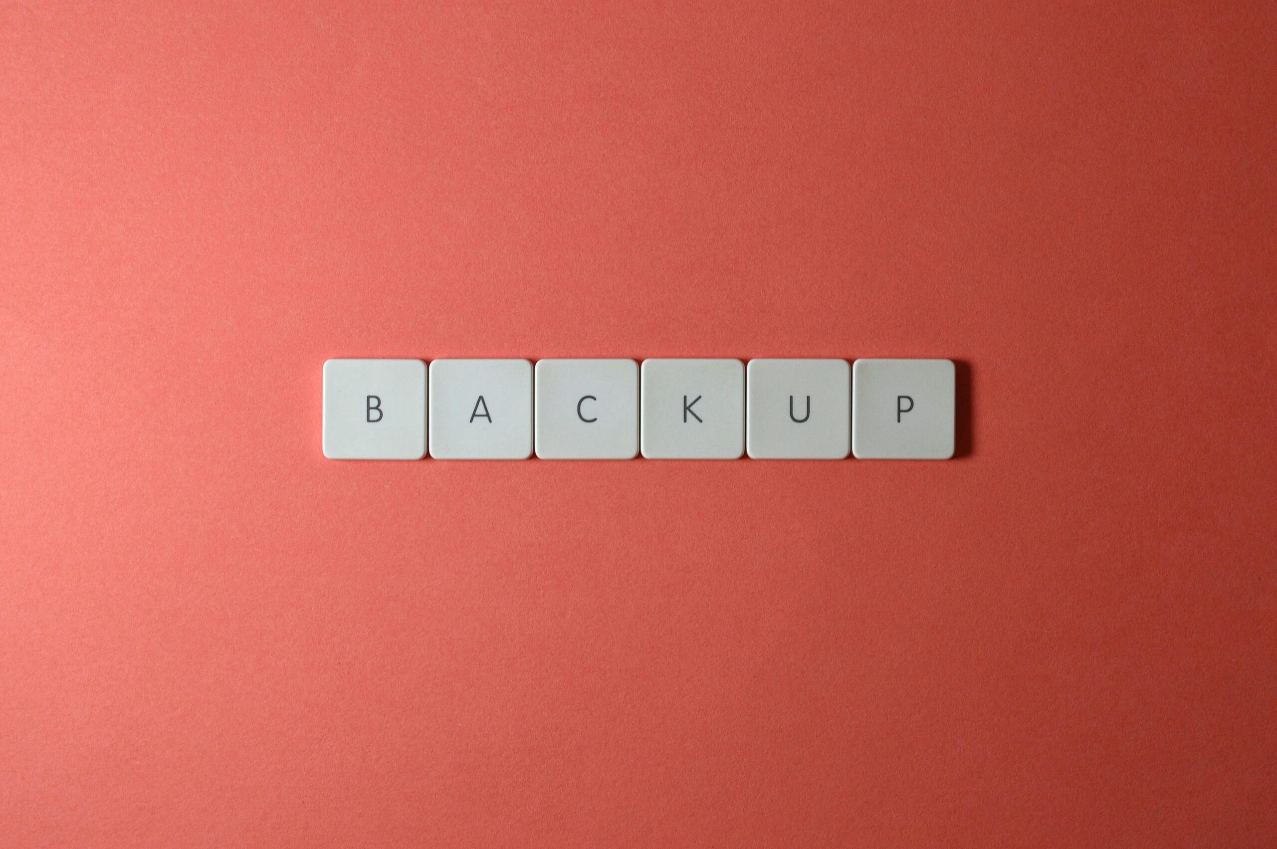 Simple Backup and Recovery Plans Every Small Business Needs 1 Free Close-up of keyboard keys spelling 'BACKUP' placed on a coral-colored surface. Stock Photo