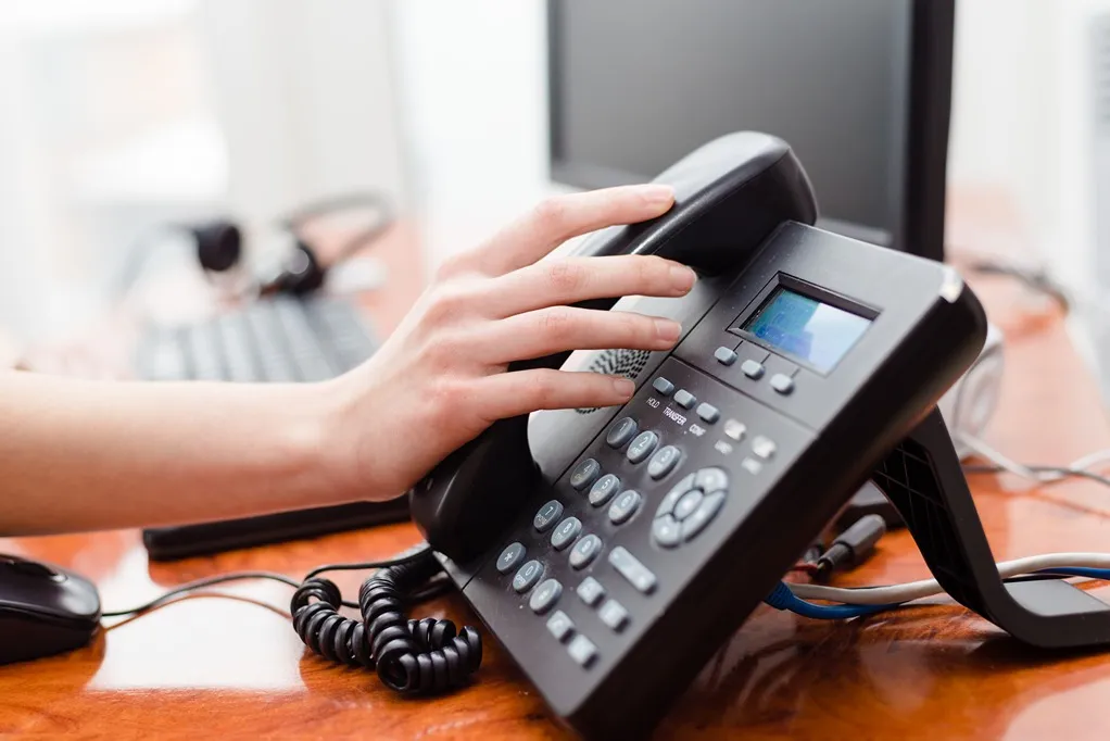 Hand pressing button on office desk phone