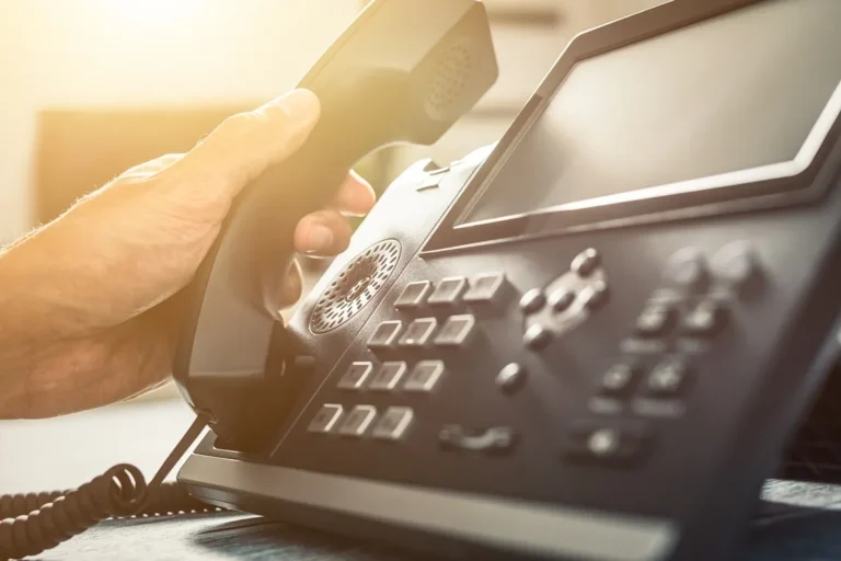 Hand picking up desk phone handset to make a call